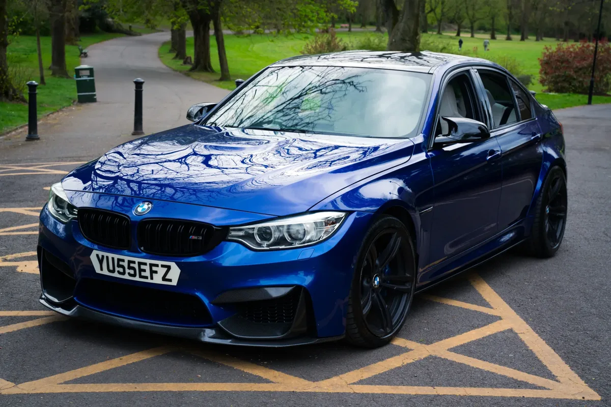 BMW M3 front three-quarter view on a parkland path