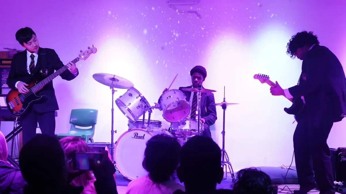 Three-piece band performing live under purple stage lighting
