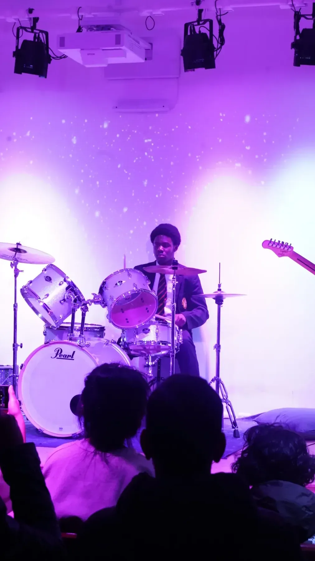 Drummer performing under stage lighting